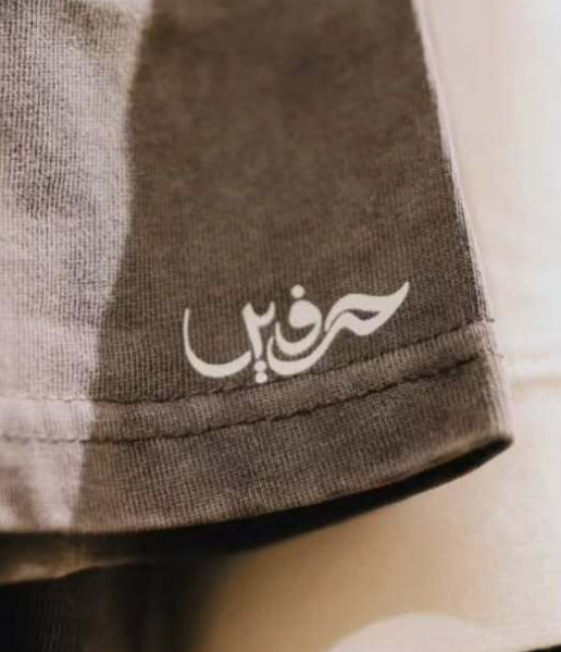 Close-up of a dark gray t-shirt with a logo on a rack of clothes.